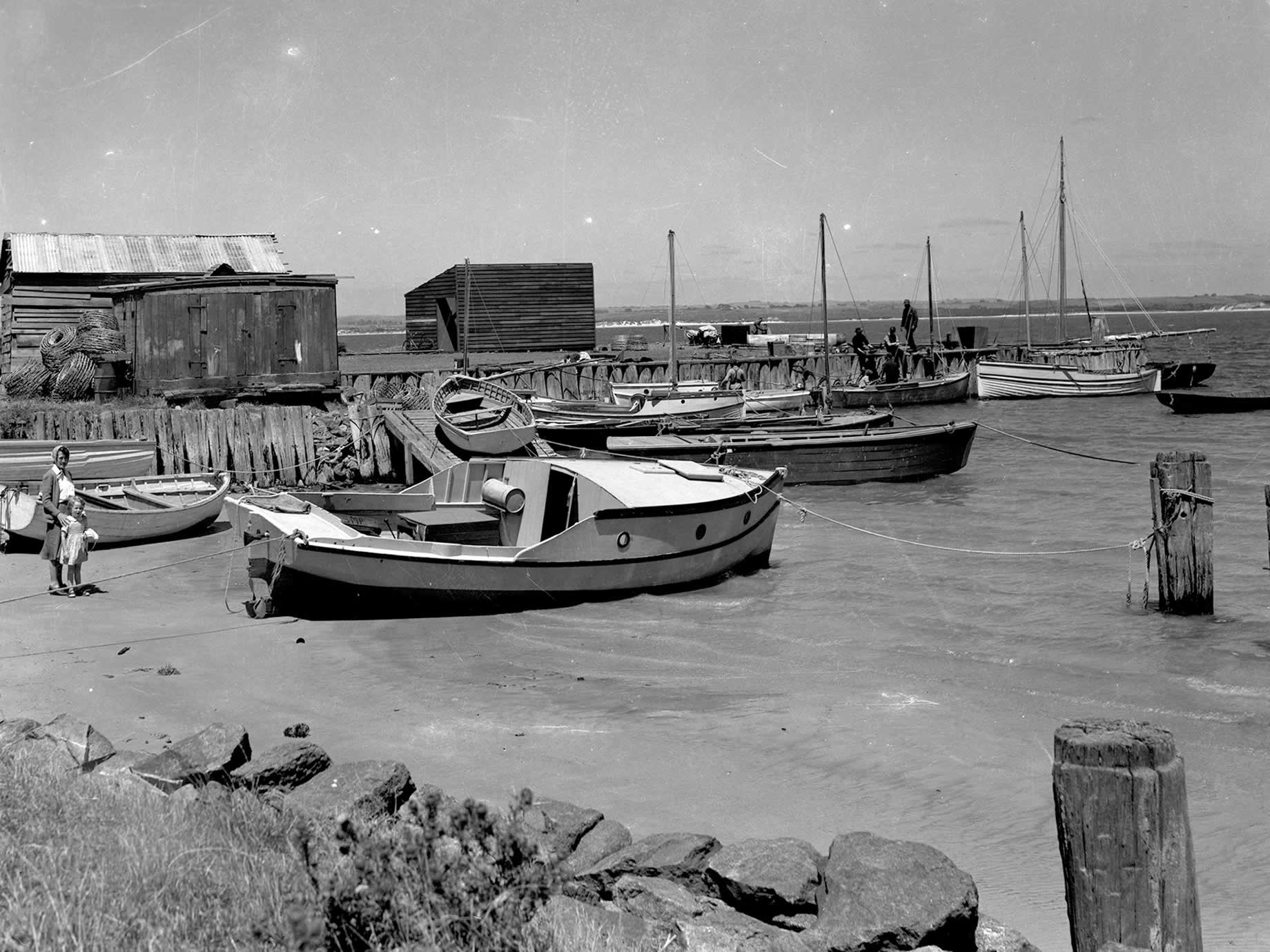 De nombreux bateaux de pêche amarrés au vieux quai, avec de plus petits bateaux au premier plan